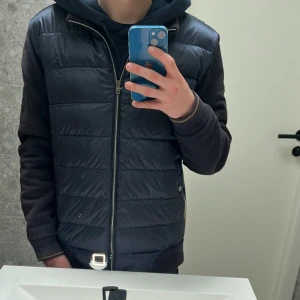 Mörkblå cardigan från Herno - Säljer en snygg mörkblå Cardigan från Herno med dragkedja och quiltad design. Cardiganen har en stilren look och passar perfekt för kommande sommar kvällar. Skick 9/10 NYSKICK🤩skriv vid minsta fundering eller för fler bilder!