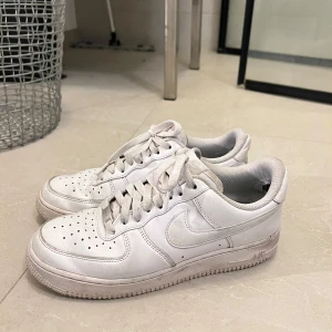 Vita Nike Air Force sneakers - Säljer ett par klassiska vita Nike Air Force sneakers. De har en rund tå och snörning framtill. Storlek 40.5