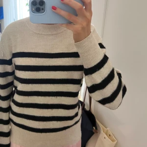 Randig beige och svart tröja - Säljer en snygg randig tröja i beige och svart. Tröjan har långa ärmar och en klassisk rund halsringning. Perfekt för en stilren och avslappnad look.