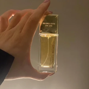 Michael Kors & Hugo Boss - Elegant body lotion från Hugo Boss, 'The Scent for Her'. Flaskan har en stilren design med en ljusrosa ton och guldiga detaljer. Perfekt för den som söker en sofistikerad doftupplevelse.