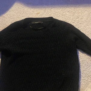 Svart stickad tröja från Vero Moda - Säljer en svart stickad tröja från Vero Moda. Tröjan har ett snyggt stickat mönster, den säljs för 100kr