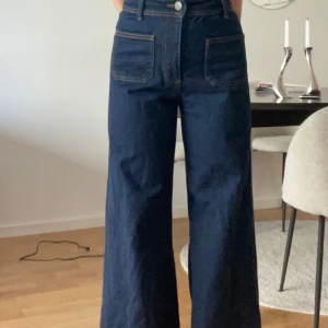 Mörkblå jeansbyxor med vida ben från Zara - Snygga mörkblå jeansbyxor med hög midja och vida ben. Byxorna har framträdande fickor både fram och bak. Storlek 36