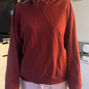 Röd hoodie - Säljer en röd hoodie med långa ärmar och en bekväm passform. Perfekt för kyligare dagar med sin mysiga huva och klassiska design. Passar bra till både jeans och mjukisbyxor.hoodie med dmå fläckar här och där,fluffig på insidan.