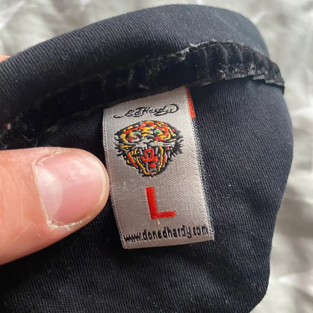Säljer en svart kortärmad t-shirt från Ed Hardy med ett stort tryck på ryggen som säger 'Death Before Dishonor'. T-shirten har en klassisk krage och är gjord i bomull. Perfekt för dig som gillar en edgy stil!. T-paidat.