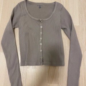 Long sleeve från Brandy Melville - Säljer en beige ribbad kofta från Brandy Melville. Den har långa ärmar och knappar framtill. 