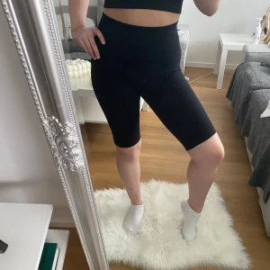 Svarta ribbade cykelshorts - Säljer ett par svarta ribbade cykelshorts. Perfekta för träning eller en avslappnad dag. De har en tight passform som ger bra stöd och komfort.