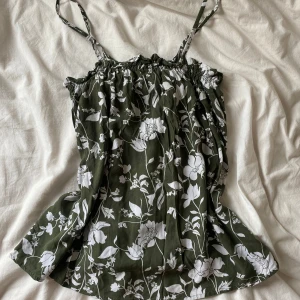 Grön blommig linnetopp från Tezenis - Säljer en grön linnetopp med vita blommor från Tezenis. Perfekt för varma dagar och enkel att matcha med jeans eller kjol. 🌸