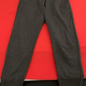 Grå kostymbyxor från Benetton - Snygga grå 7/8 kostymbyxor från Benetton med diskret prickigt mönster. Byxorna har normal passform, bälteshällor och stängs med dragkedja och knapp. Perfekta för en stilren look.