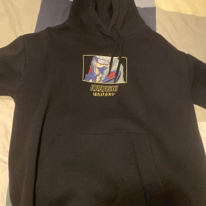 Svart Naruto Kakashi hoodie från Pull&Bear - Svart hoodie med stor tryck av Kakashi från Naruto både fram och bak. Tröjan har huva med dragsko och stor magficka. Perfekt för animefans som vill sticka ut med en cool och bekväm stil.