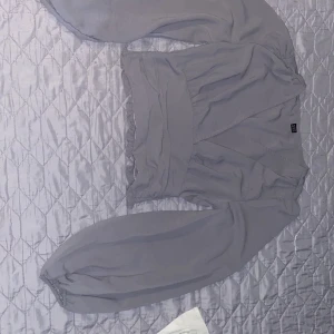 Ljuslila omlottblus från SHEIN - Säljer en ljuslila omlottblus från SHEIN med långa puffärmar och bred midjeresår. Blusen har v-ringning och är tillverkad i ett lätt, syntetiskt material. Perfekt för dig som gillar feminina detaljer och en trendig look.