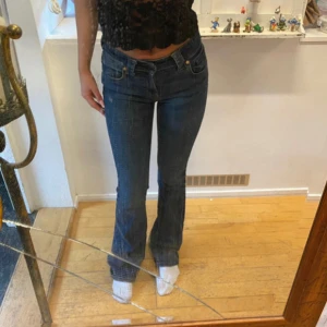 Blå bootcut jeans - Snygga blåa bootcut jeans med klassisk femficksdesign och låg midja. Jeansen har en lätt tvättad look och stängs med dragkedja och knapp. Perfekta för en avslappnad stil.