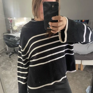 Svart och vit randig stickad tröja - Säljer en svart stickad tröja med vita horisontella ränder, har en slits på båda sidor, från gina tricot i strl xs.