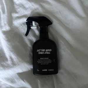 Let The Good Times Roll Body Spray från Lush - Säljer en svart sprayflaska med body spray från Lush, 'Let The Good Times Roll'. Flaskan rymmer 200 ml och har en enkel, modern design med vit text på framsidan. Perfekt för dig som gillar söta och popcorn-inspirerade dofter. Lite mer än hälften kvar!