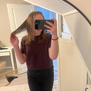 Mörklila croppad t-shirt - En enkel och stilren mörklila croppad t-shirt med rund halsringning. Perfekt att matcha med både jeans och kjol för en avslappnad look. T-shirten har korta ärmar och är tillverkad i ett mjukt material.