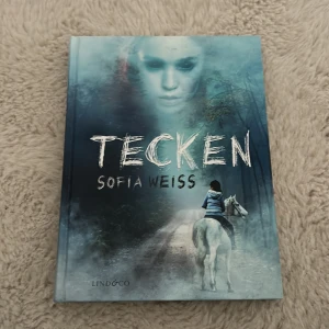 Tecken - Säljer boken 'Tecken' av Sofia Weiss. En spännande rysare. Omslaget har en mystisk blå ton med en ryttare på en vit häst och ett spöklikt ansikte i dimman. Perfekt för dig som gillar mysterier och skräckböcker.