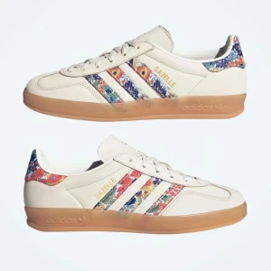 Adidas Gazelle x Liberty London sneakers  -  Säljer ett par HELT NYA Adidas Gazelle x Liberty london sneakers. 🗽💐 Skorna har blommiga detaljer på hälen och de klassiska tre ränderna.  Levereras i originalkartong med extra skosnören 😊 ‼️Har två par i olika storlekar, helt nya med prislapp och kartong kvar (aldrig använda). Dessa skor är dessutom helt utsålda hos addidas‼️ STORLEK: 38 och 2/3 NYPRIS: ca 1600kr