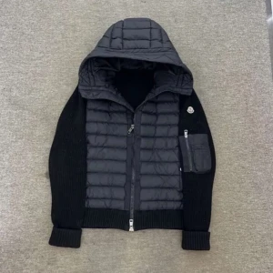 Svart hybridjacka med huva från Moncler - Snygg svart jacka från Moncler med quiltad front och stickade ärmar. Jackan har huva, dragkedja framtill och en praktisk ficka med dragkedja på ärmen. Perfekt för dig som vill ha en sportig och stilren look. Den har ett litet hål under vänster arm 