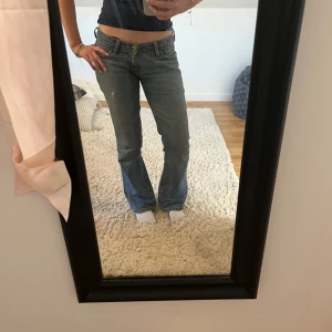 Blå bootcut jeans från Levis - Säljer ett par klassiska blå bootcut jeans från Levis med låg midja. snygga sömmar på bakfickorna. Perfekta till vardags och lätta att matcha med olika toppar. Midja: 38 tvärs över innerbenslängd: 78 cm passar mig som är 164 men blir npg lote för korta om man är längre