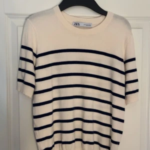 Vit och marinblå randig tröja från Zara - Säljer en vit tröja med marinblå ränder från Zara. Tröjan har korta ärmar och rund halsringning. Materialet känns mjukt och lätt, perfekt för vår och sommar!💞Den är liten i storlek. Storleken är M men känns som S/XS ( använd 1 gång )