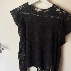 Svart spetsblus från Charlotte Russe - Säljer en svart blus från Charlotte Russe som är köpt för 500 kroner i usa. Vacker spets med blommönster. Blusen har korta ärmar och rund halsringning. Perfekt för dig som vill ha en elegant och stilren topp med fina detaljer.