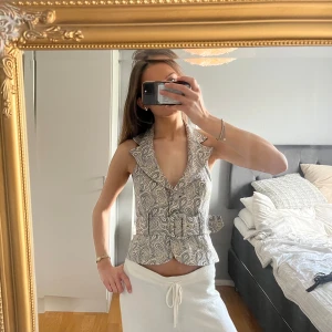 Mönstrad korsettväst - Säljer en snygg unik topp med fint mönster och öppen rygg!