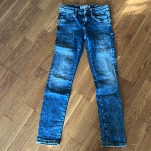 Blå stretchjeans från Denim & Run - Säljer ett par blå stretchjeans från Denim & Run i storlek 152. Jeansen har klassisk femficksdesign, dragkedja och knapp, samt justerbar midja med knappresår. De har en straight passform och är perfekta för vardagslooken.