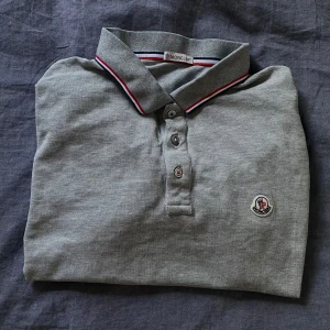  Moncler pikétröja - Stilren grå pikétröja från Moncler. Tröjan är i storlek L men passar som en M/S. Är i mycket bra skick och inga defekter! Perfekt inför sommaren💫              Skriv ifall ni har några frågor🙌🏻