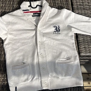 Unik cardigan från bondelid - En otroligt snygg cardigan från Bondelid😍Cardiganen är mycket fräsch och unik. Skick 10/10.  Färgen är krämvit/ljusgrå med röda och blå detaljer. Size L men passar M också. Perfekt för lite kyligare väder i sommar☀️🌄Sitter otroligt bra. Bara att höra av er om ni är intresserade eller behöver mer bilder, pris kan diskuteras💰