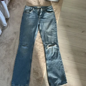 Blå jeans med slitning från Gina - Säljer ett par blå jeans från Gina tricot med lite bootcut och slitning vid knät. Klassisk femficksmodell med normal passform och dragkedja i gylfen. Perfekta för en avslappnad stil.💙