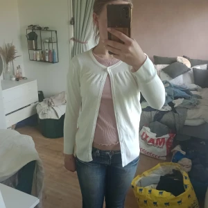 Vit kofta från vero moda  - Säljer en klassisk vit kofta från Vero moda. Koftan har rund halsringning, långa ärmar och knäppning framtill. Perfekt att slänga över en topp eller klänning för en enkel och stilren look. Strl M