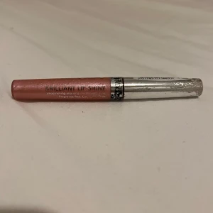Brilliant Lip Shine läppglans i rosa - Säljer en Brilliant Lip Shine läppglans i en skimrande rosa nyans. Tuben har förstörts av vatten men inga fel, oöppnad. Perfekt för att ge läpparna glans och en hint av färg.