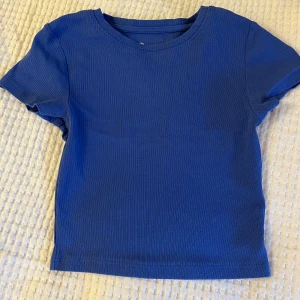 Blå ribbad t-shirt - Blå ribbad croppad tshirt från new yorker. Använt ganska mycket men fortfarande bra skick storlek Xs.