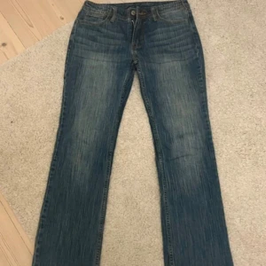 Blå jeansbyxor med raka ben - Klassiska blå jeansbyxor med raka ben och normal passform. Jeansen har fem fickor, knapp- och dragkedjegylf samt diskreta slitningar för en avslappnad look. Perfekta för dig som gillar en tidlös stil.