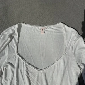Vit långärmad topp med spetskant - Säljer en vit långärmad topp från Nelly med v-ringning och fin spetskant runt halsen. Storlek L. Använd två gånger så fint skick