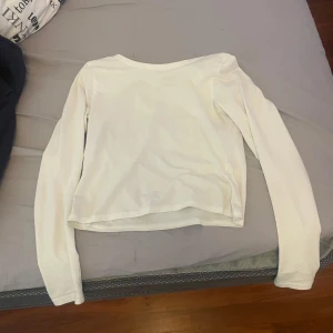 Vit långärmad topp från H&M - Säljer en enkel och stilren vit långärmad topp från H&M Divided. Modellen är croppad och har en rund halsringning
