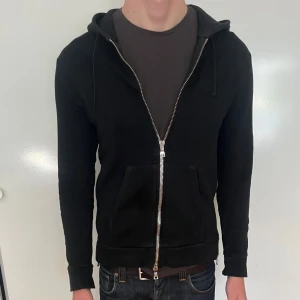 Svart hoodie från Balmain - Säljer en svart hoodie från Balmain med dragkedja framtill och på sidorna. Den är använd, men har hållits i bra skick. Inget synligt slitage. 