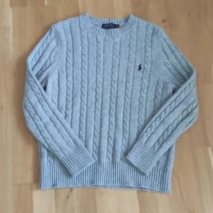 Kabelstickad Ralph Lauren tröja - Riktigt fin grå kabelstickaf tröja från märket Ralph Lauren I utmärkt skick. 