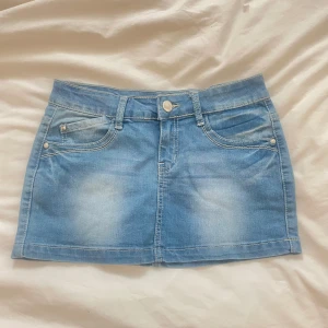 Ljusblå jeanskjol med fickor - Superfin blå jeanskjol med fickor fram och bak, samt snygga detaljer i spets på bakfickorna, skulle säga att den passar xs-s💗Den är stretchig, midjemått tvärs över: 35cm. Längd:29cm.