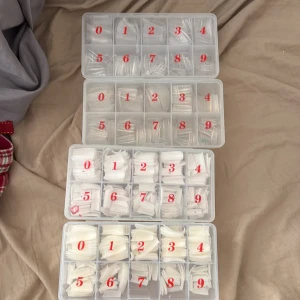 Stora set med lösnaglar i olika storlekar - Fyra askar fyllda med lösnaglar i både transparent och vit plast. Naglarna är sorterade i fack märkta 0-9 för olika storlekar. Perfekt för dig som vill fixa snygga naglar hemma och testa olika former och längder.