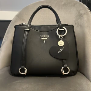 Svart handväska från Guess  - Säljer min super fina Guess väska då den inte kommer till användning. Väskan är i superfint skick💕