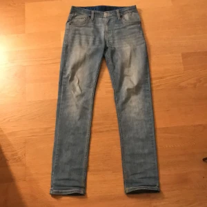 Levi's 502 ljusblå jeans - Säljer ett par klassiska Levi's 502 jeans i ljusblå tvätt. Jeansen har fem fickor, raka ben och normal passform. De är tillverkade i mjukt denim och har snygga slitningar framtill för en avslappnad look. Perfekta för dig som gillar en tidlös stil. Märket är lite skadat där bak på byxorna, finns bild på det👍🏼