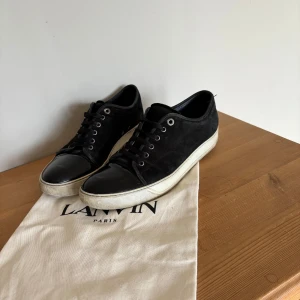 Svarta sneakers från Lanvin i mocka - Säljer ett par svarta lanvins, påsen ingår. Dom är i fint skick förutom slitage vid hälen vid innifrån sidan (se sista bilden) men det går att fixa hos en skomakare för typ 200kr. Priset är inte hugget i sten.