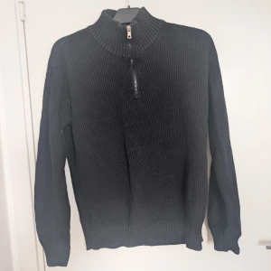 Svart stickad tröja med half zip - Svart ribbstickad tröja med hög krage och half zip-dragkedja framtill. Strl 158/164 (stor i storlek) motsvarar en S i herr.