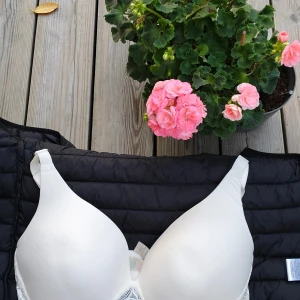 Vit spetsdetaljerad bh 90E ECO - Snygg vit bh i storlek 90E från ECO med vadderade kupor och fina spetsdetaljer längs kanterna och ryggen. Justerbara axelband och bred knäppning bak för extra stöd. Perfekt för dig som vill ha både komfort och stil.