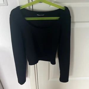 Svart långärmad topp från Bershka - En stilren svart långärmad topp från Bershka med rundad halsringning och croppad passform. Perfekt att matcha med höga jeans eller kjol för en enkel men snygg look.