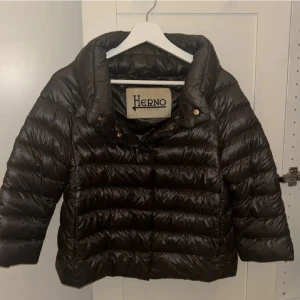  pufferjacka från Herno - Säljer en grå pufferjacka från Herno med bred krage och trekvartsärmar. Jackan har en snygg quiltad design och stängs med knappar framtill. Perfekt för dig som vill ha en stilren och cool look under kyliga dagar. Jackan är i storlek S/42IT