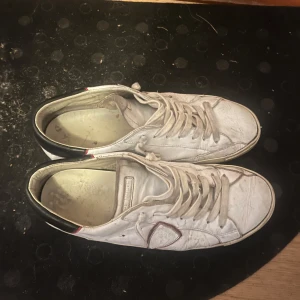 Vita sneakers från Philippe Model - Hej! Jag säljer ett par skor från Phillippe Model. Dessa är perfekt för dig som inte vill spendera för mycket pengar och bryr dig inte om det är ett litet slitage på skorna, baksidan av sulan är lite trasig men det är inget som inte går att fixa, sulorna på insidan är slitna men jag skickar med ett par andra sulor så känns dom som nya!