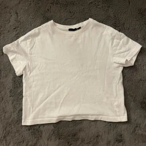 Vit croppad t-shirt - Enkel och stilren vit croppad t-shirt med rund halsringning och korta ärmar. Perfekt basplagg i mjuk bomull som passar till allt. Snygg att matcha med jeans eller kjol för en clean look.