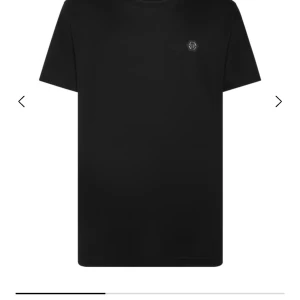 Svart t-shirt från Philipp Plein - Svart t-shirt från Philipp Plein med diskret logotyp på bröstet. Klassisk rund hals och korta ärmar. Perfekt för dig som gillar stilrena och enkla plagg med en exklusiv touch. Materialet känns mjukt och bekvämt mot huden. Alltså märket sitter i mitten ny model men hittade ba denna bilden hör av er vid köp eller bud nfc scanning finns 🙂👍