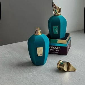 Xerjoff Erba Pura Eau de Parfum - Lyxig parfym från Xerjoff, Erba Pura, i en unik turkos flaska med guldiga detaljer och elegant, snedställd guldkork. Flaskan har en matt yta och geometrisk form, och levereras i en exklusiv lila och turkos ask med gulddetaljer. Perfekt för dig som gillar statement-dofter.